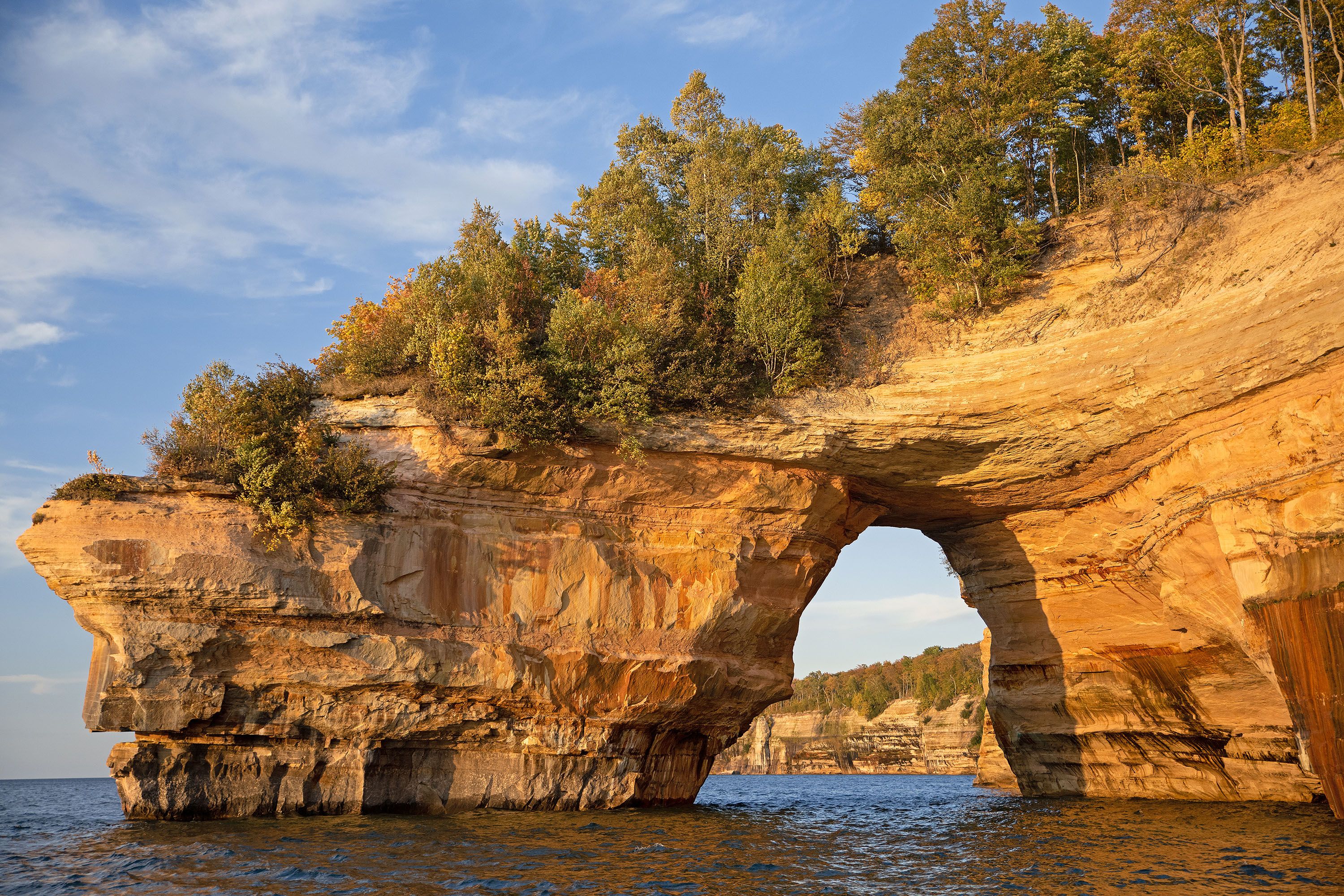 A rock formation with an arch, trees growing on top of it.
