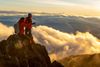 Two hikers at the top of the Barú Volcano, the highest peak in Panama, looking out over clouds beneath them
