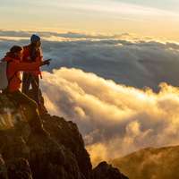 Two hikers at the top of the Barú Volcano, the highest peak in Panama, looking out over clouds beneath them