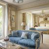 A suite at The Ritz Paris, with a blue sofa and lavish bedroom seen beyond