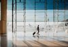 View on the aiport window with woman walking with suitcase at the departure hall of the airport.