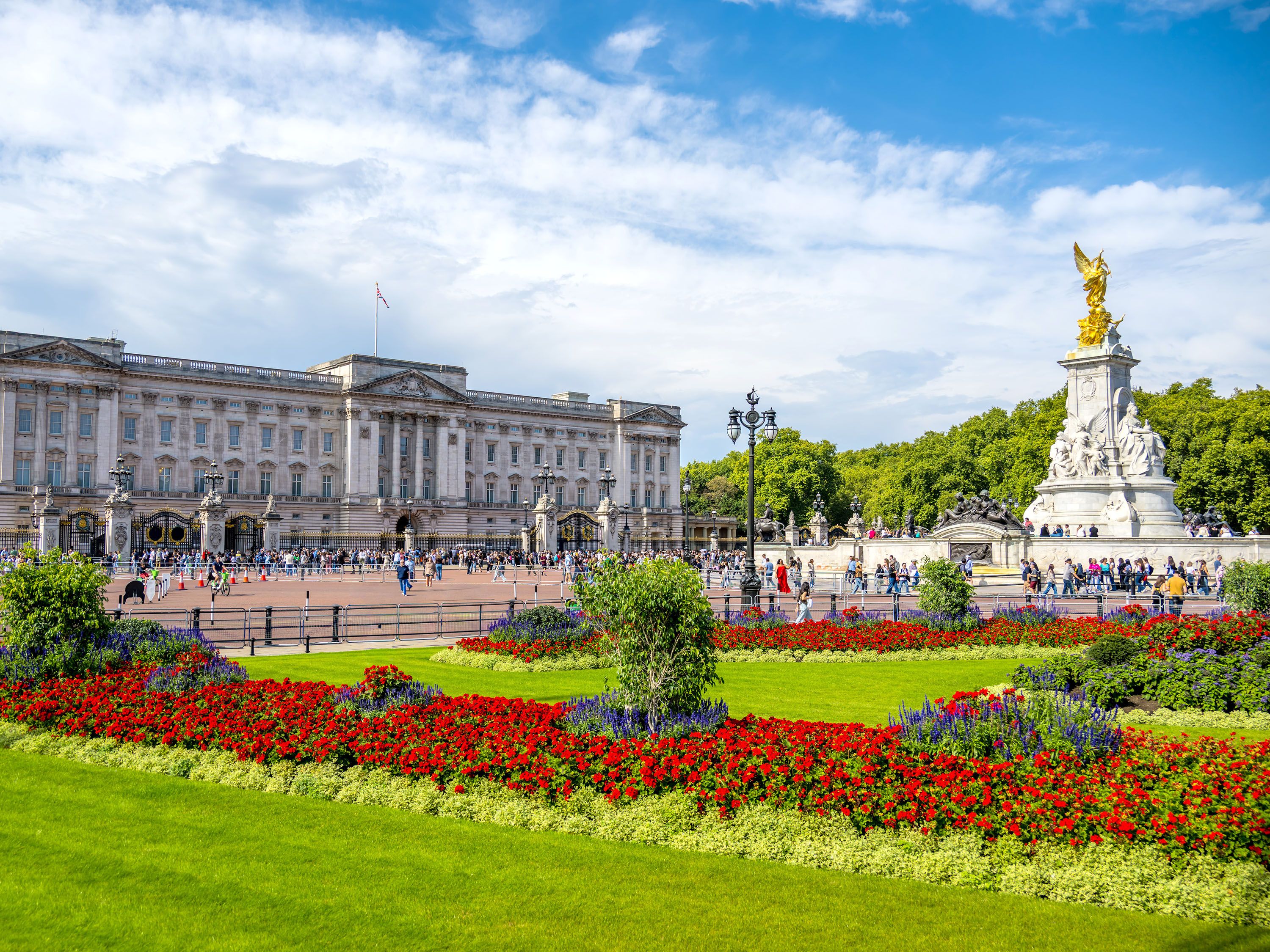 Flower garden in front of Buckingham Palace with statue.