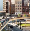 A trainline running over a road in Detriot, with skyscrapers in the background