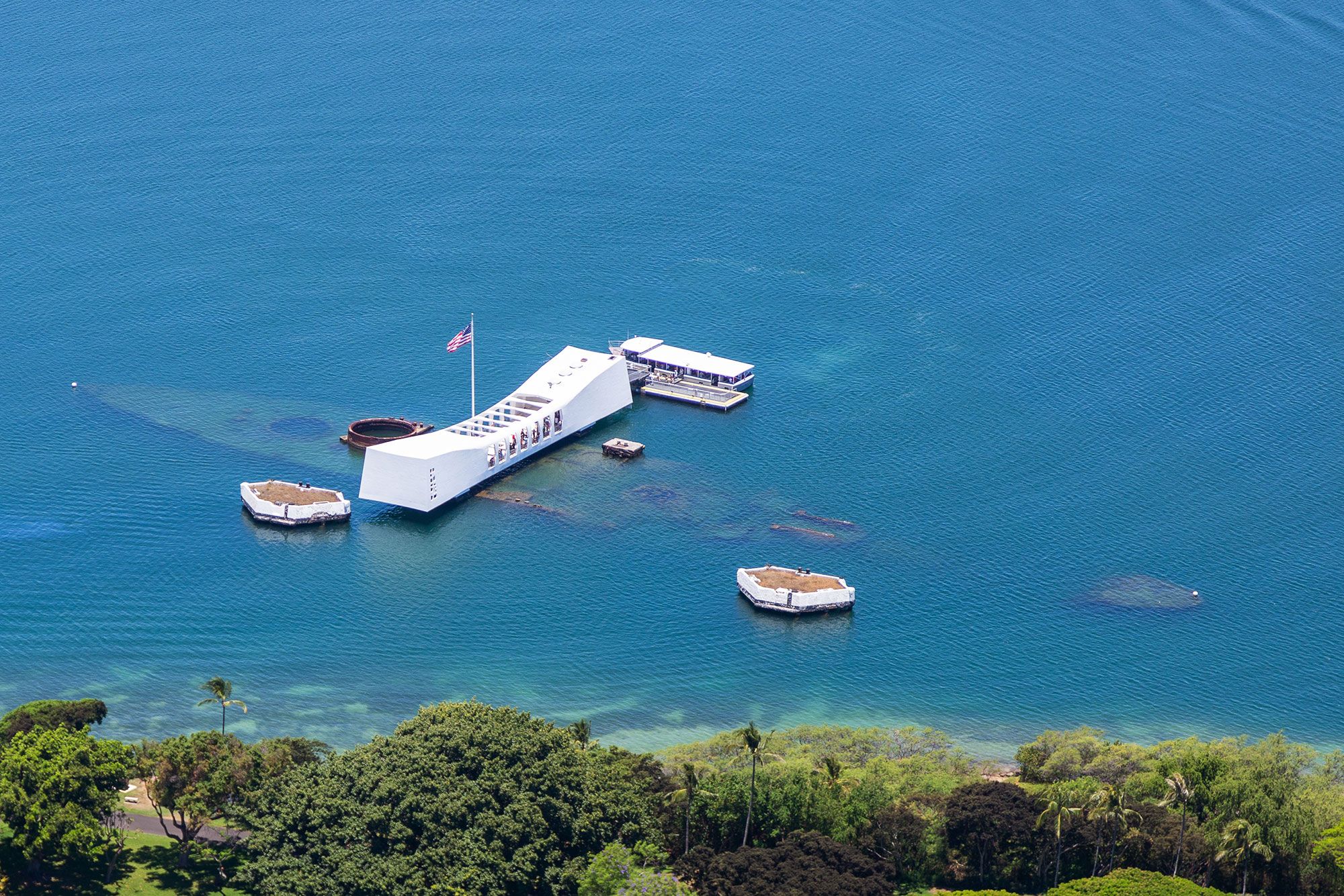 Aerial view of a white structure floating on water on top of a sunken ship.  