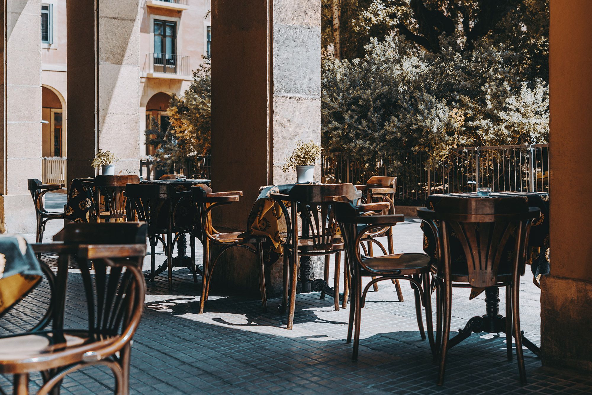 An outdoor cafe with tables and chairs setup with the light shining outside.