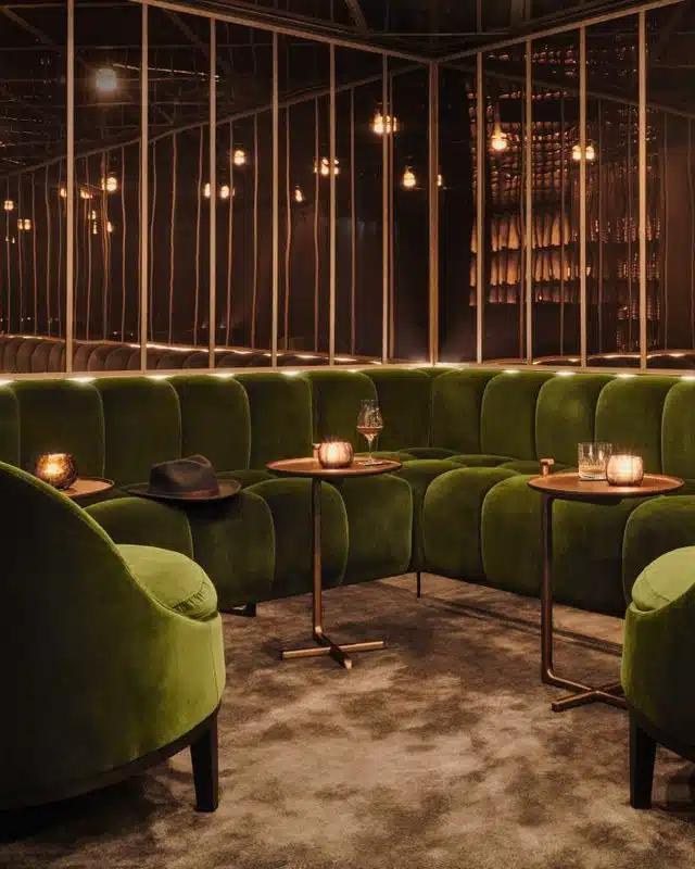 The green velvet sofas and rose gold, mirror-lined walls in the bar at The Londoner hotel in London, U.K.