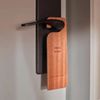 A wooden tag hangs from a hotel room door handle, engraved with the words 'Going green - don't make up my room'