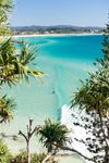 A surfer paddles over a wave in the turquoise waters of Greenmount Beach on Queensland's Gold Coast in A