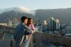 Two men on a balcony look out over the city with Table Mountain and floa overlooking a city with