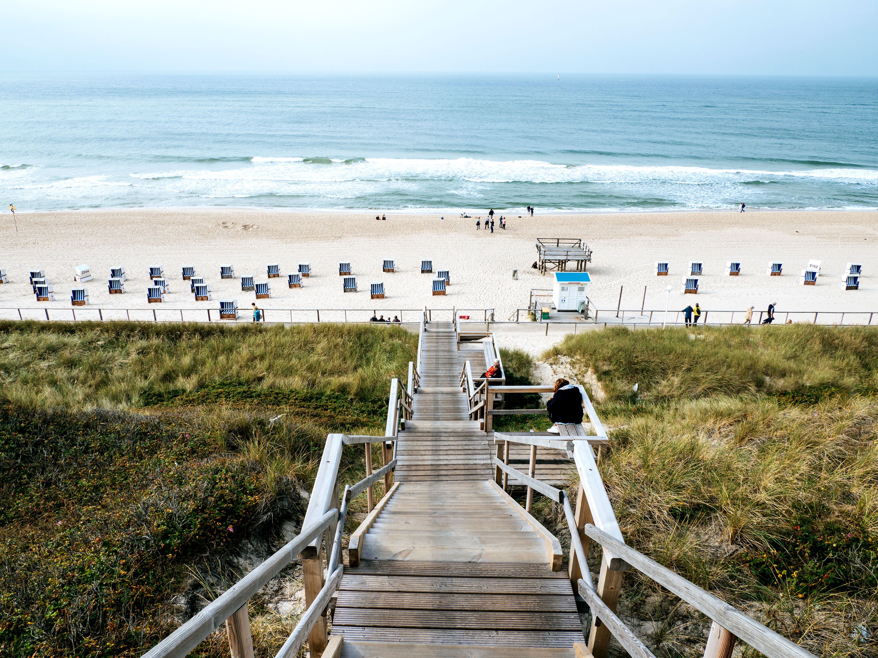 Steps down to a beach area with chairs and ocean view.