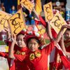 Young girls in red costume wave signs reading "Tết" in the air during the Tết Parade in Wetminster, CA