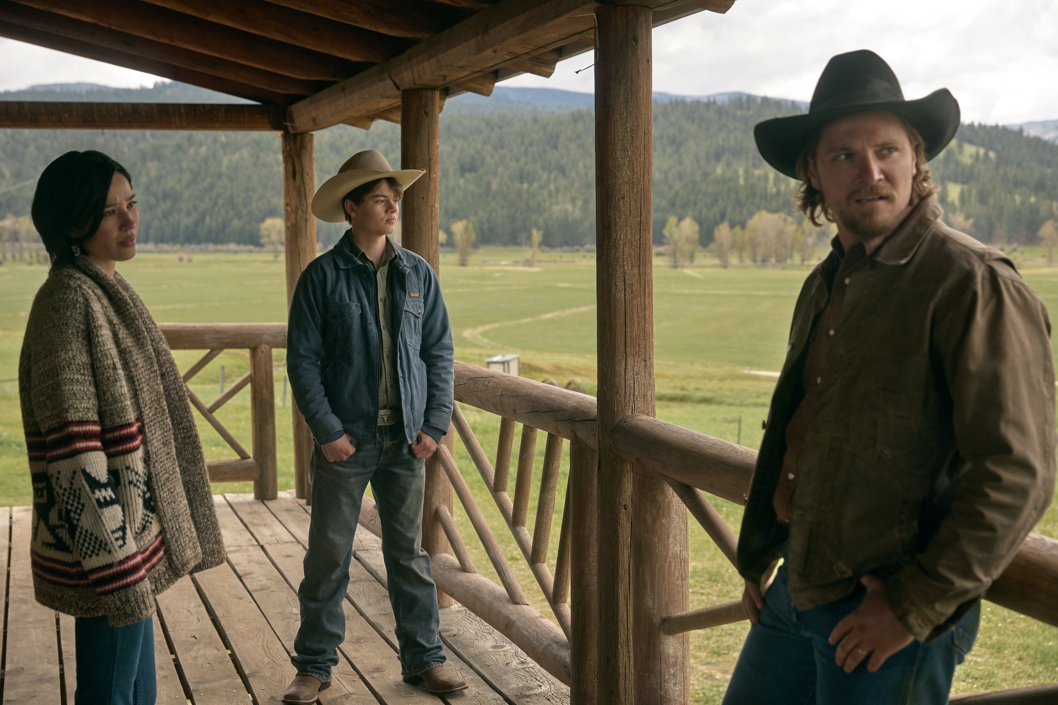 A still from Yellowstone, with the characters Monica, Tate and Kayce Dutton, on a porch, with the countryside beyond (courtesy of Paramount Network)