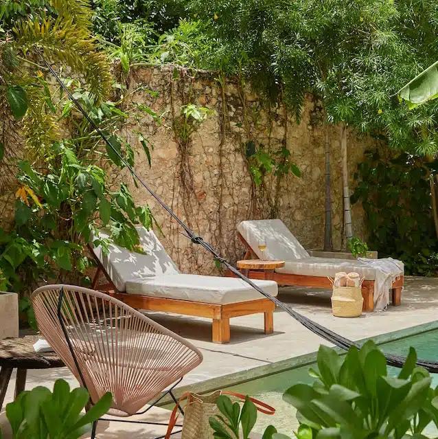 Sun loungers beside a pool in a garden of a Vrbo in Mérida, Mexico