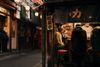 People sit at stools around the bar of a warmly lit izakaya on Omoide Yokocho in Tokyo, Japan