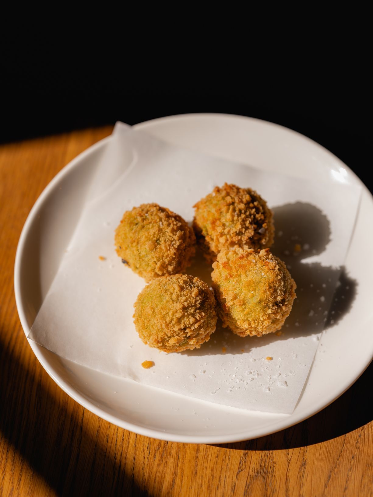 A white plate holds four arancini, or fried risotto balls; they're a Sicilian staple