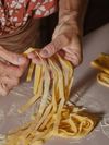 A close-up of someone making tagliatelle by hand