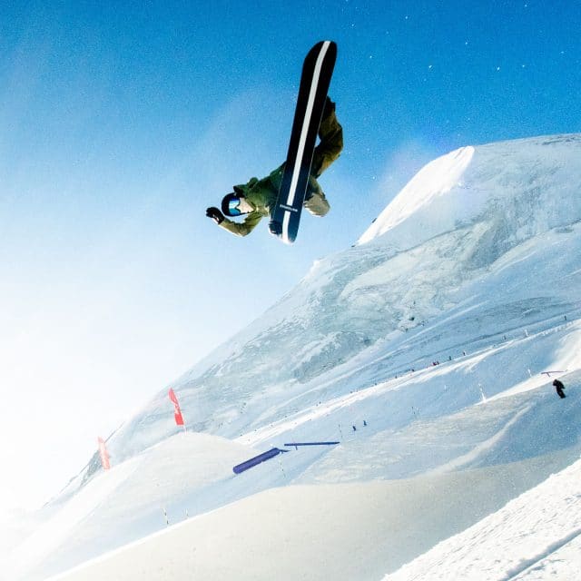 Shaun White performs a snowboard trick in the air on snow-covered slopes
