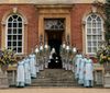 Footmen and maids line the stairway in front of Kingston Bagpuize House, Oxfordshire, in a scene from Bridgerton