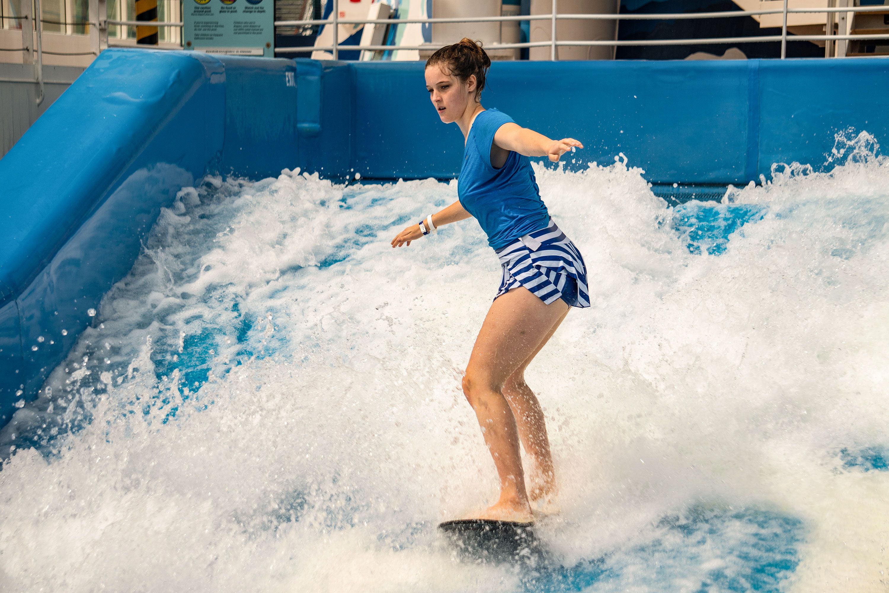 Woman on a floboard surfboard in wave pool on wave.
