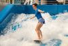 Woman on a floboard surfboard in wave pool on wave.