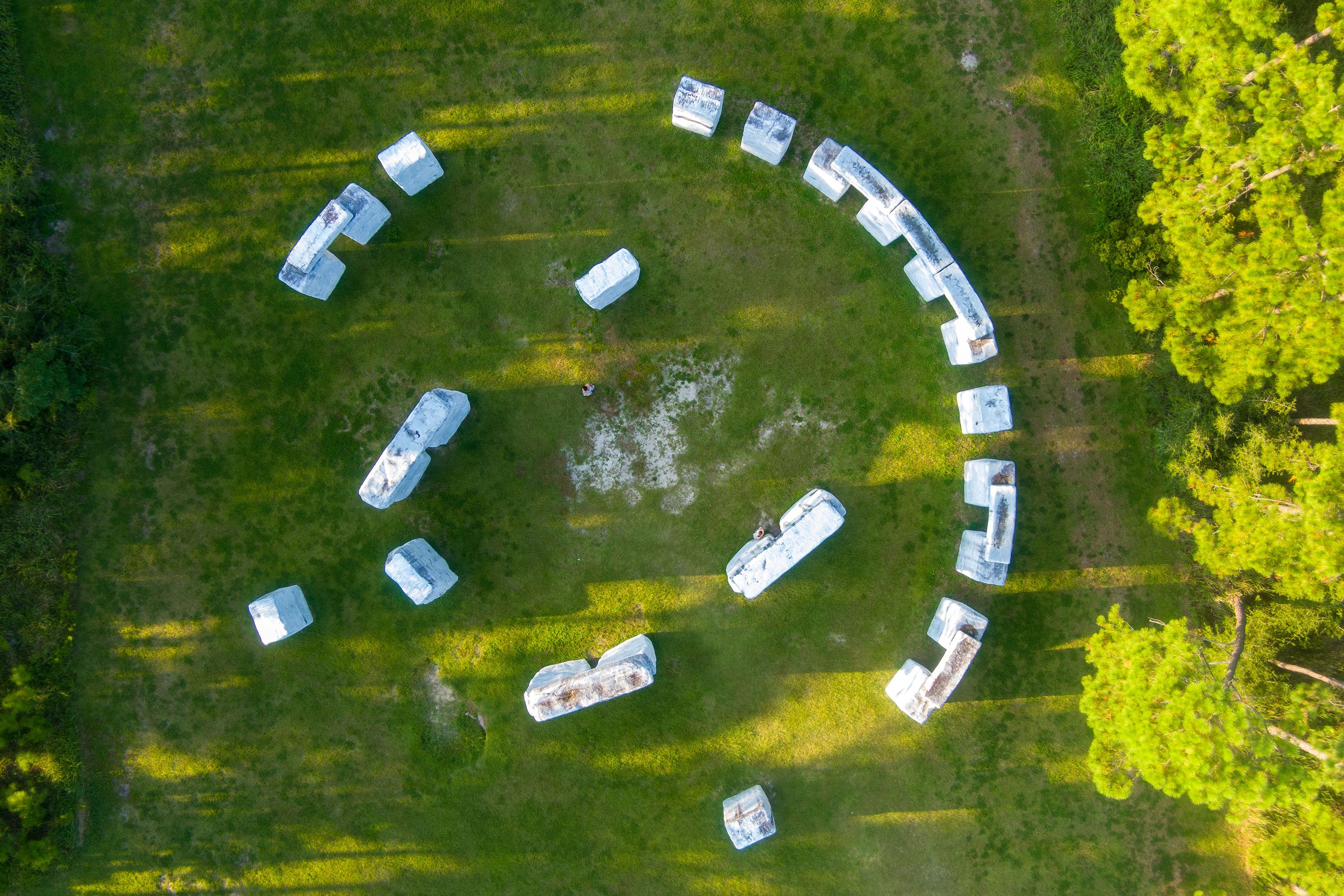 An aerial view of a stone circle installation set in a grassy field.