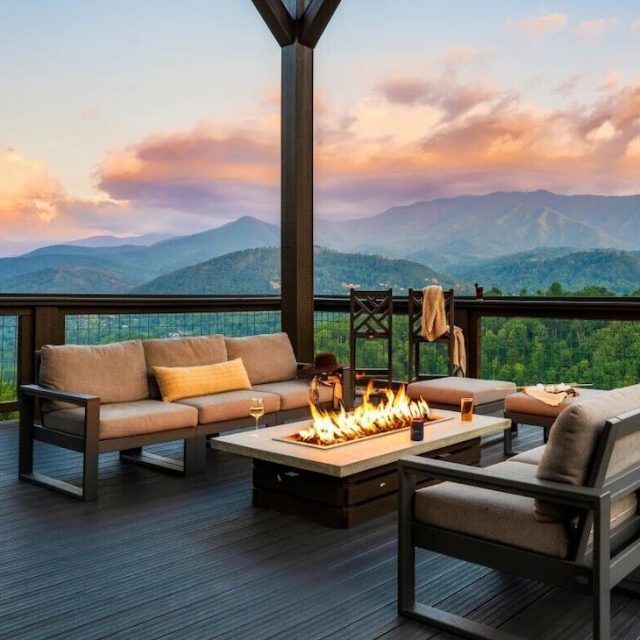 A view of mountains and pink clouds from the deck of a Vrbo in Gatlinburg, Tennessee, with a firepit and comfortable seating