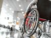 Person rests hand on wheelchair wheel in midway of airport.
