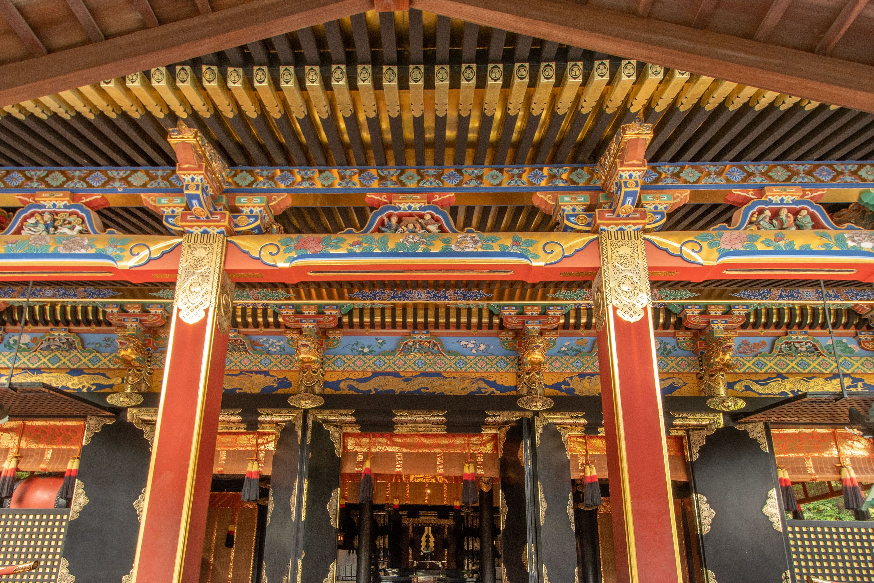 Colorful red and gold shrine buildings of Kunōzan Tōshō-gū nestled among trees on a hillside in Shizuoka.
