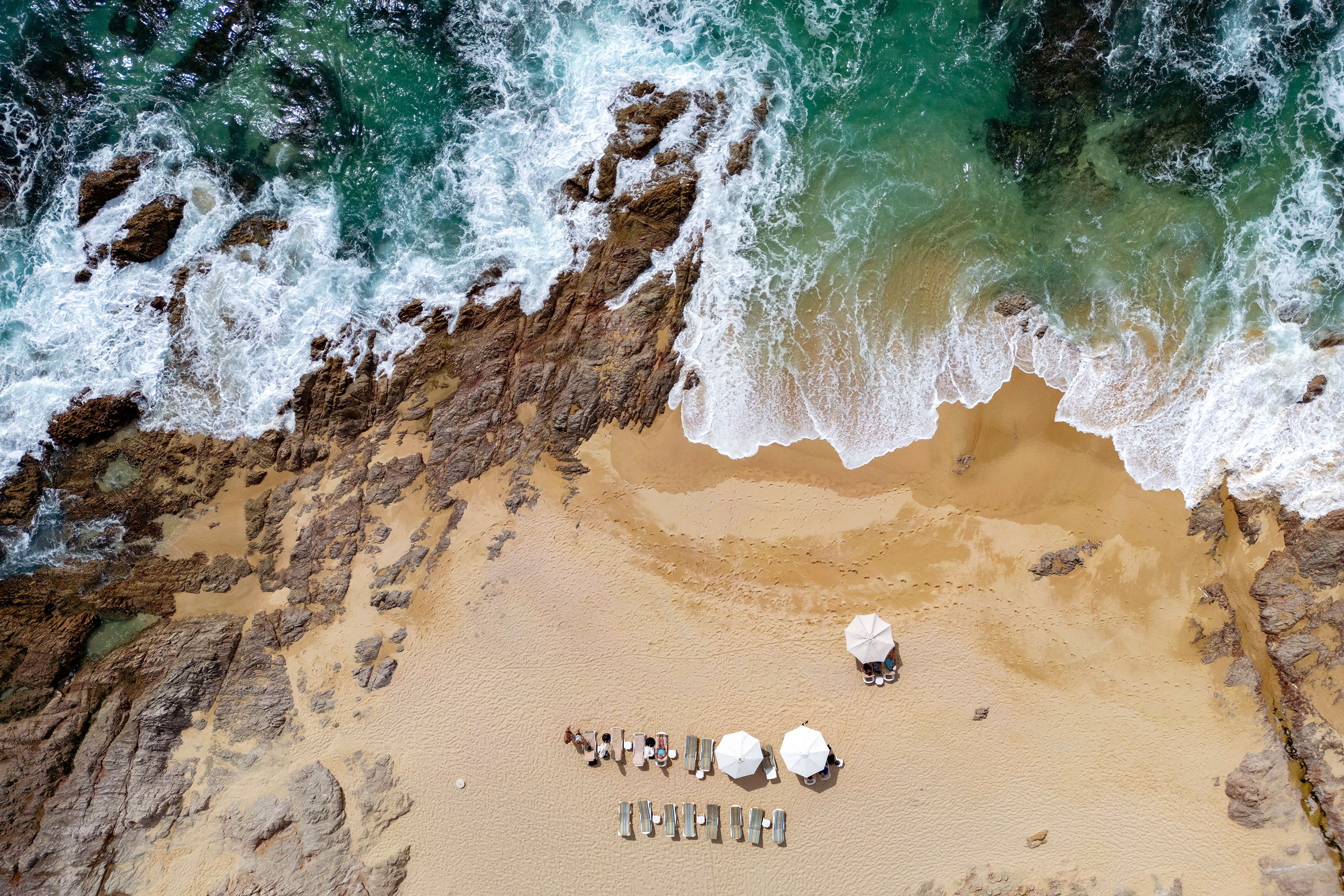 Aerial view of umbrellas and chairs laid out on a beach in Cabo San Lucas, Mexico.
