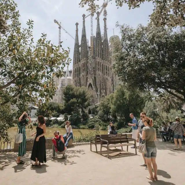 People hang out in the park beside the Sagrada Família in Barcelona, Spain