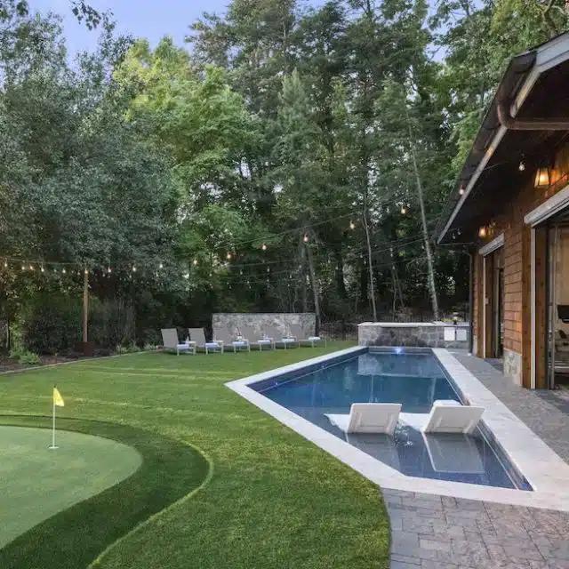 A putting green beside an angular pool at a Vrbo near Charlotte, NC