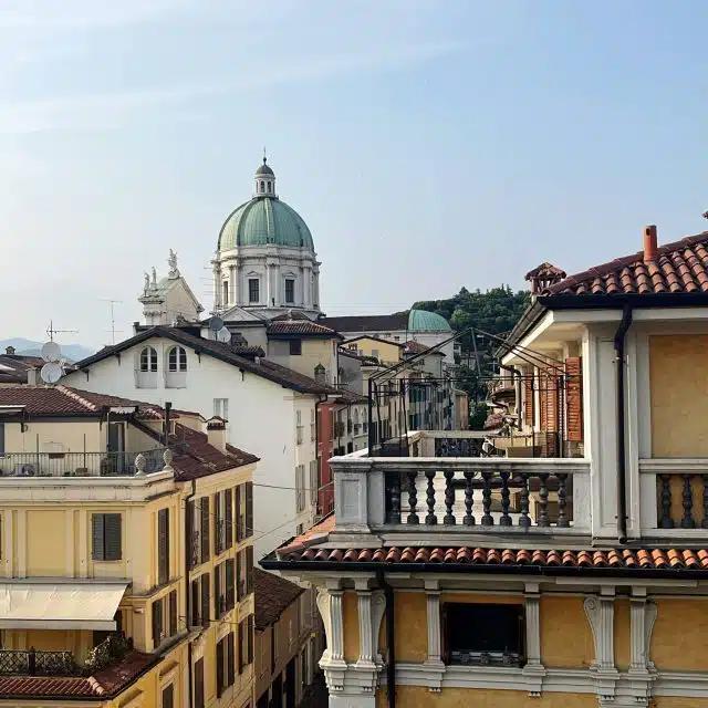The Romanesque Duomo is seen over the top of buildings in Brescia, Italy