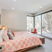 The bedroom with floor-to-ceiling windows looking out onto snow-covered trees at a Vrbo rental chalet in Winter Park, Colorado