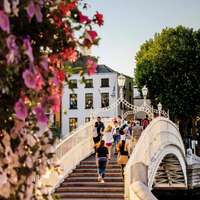 People walk over the Ha'penny Bridge on a sunny day in Dublin, Ireland
