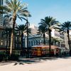 A red and yellow New Orleans streetcar under the shade of palm trees