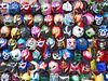 Rows of colorful masks hang on a wall.