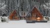 A-frame cabin with glass walls in a snowy forest, showcased by Vrbo as an ideal vacation rental for a serene mountain getaway.