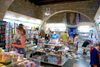 People shopping for books and art gifts inside a museum store with stone arches.