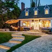 A house lit up from the inside, with a dining area outside
