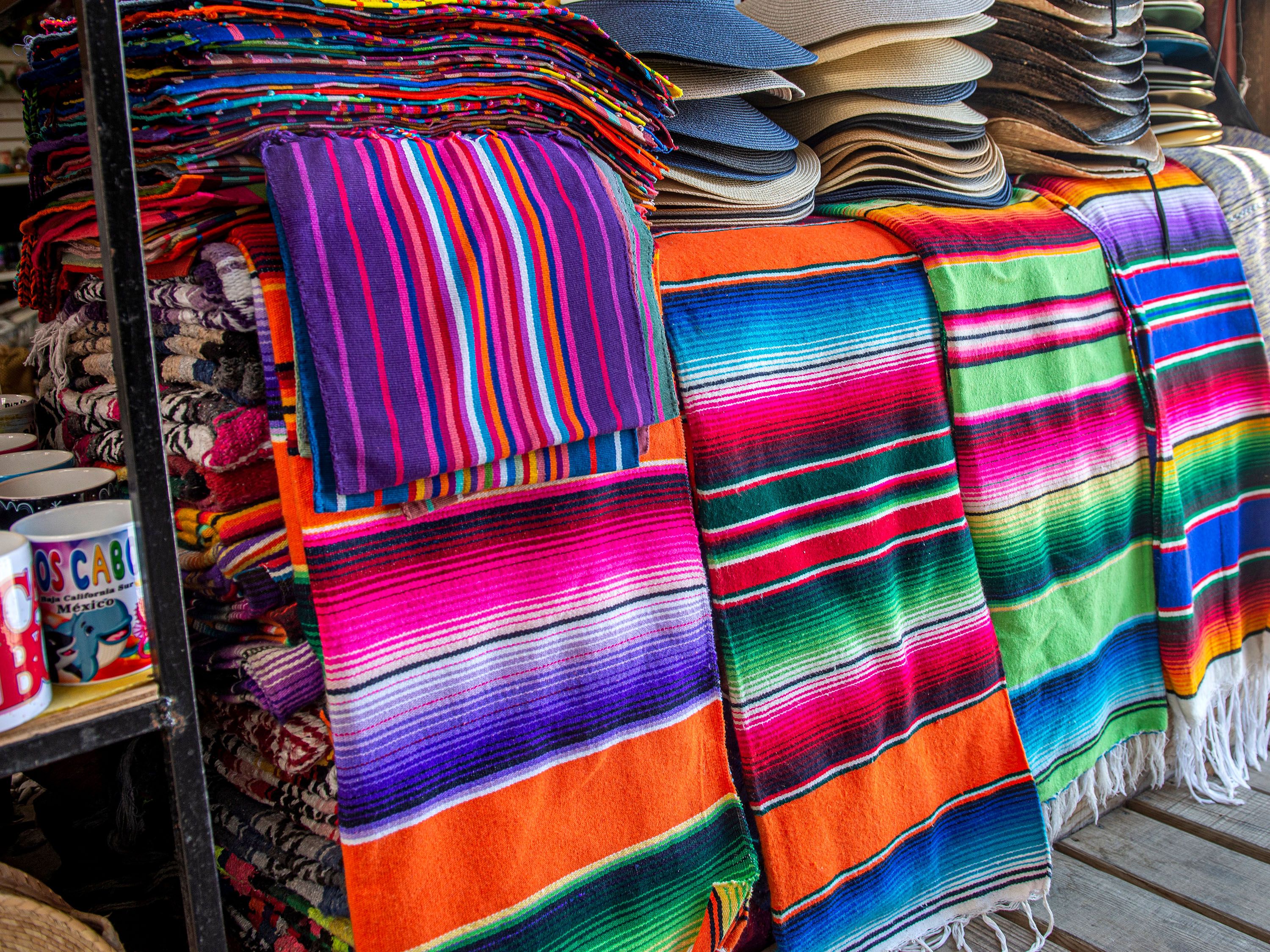 Pink, purple and white striped tapestries and hats on a table.