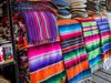 Pink, purple and white striped tapestries and hats on a table.