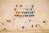 Overhead view of yellow and blue beach umbrellas and people laying in the sun on a beach in Miami.