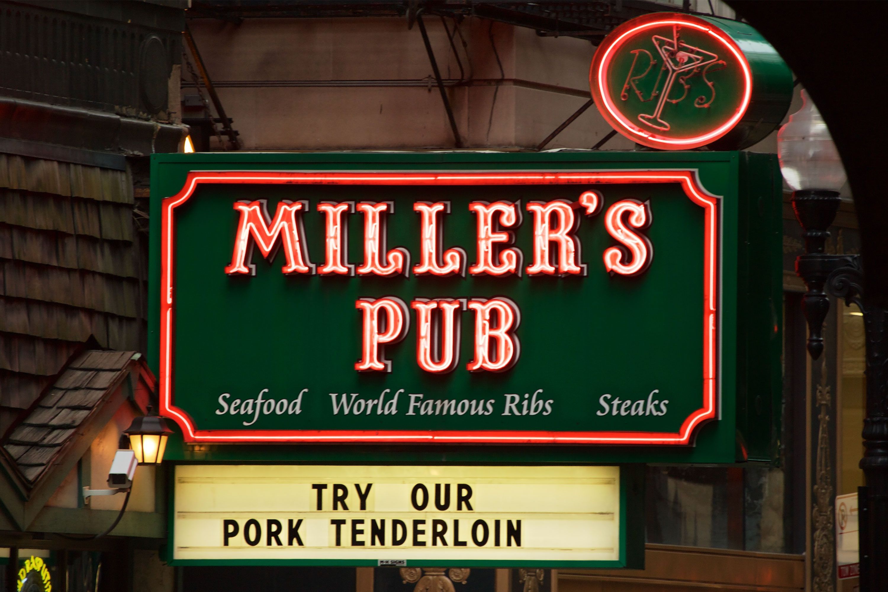 An exterior view of Miller’s Pub in Chicago, showing its vintage neon sign and brick storefront along a busy city street.