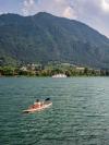A person kayaks across Lake Iseo in Brescia, Italy, with mountains in the distance