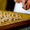 Laid out precisely along small strips of pasta dough, little chunks of meat filling are arranged ready to be rolled into tortellini