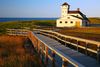 The historic wooden Race Point Coast Guard life-saving station building on sandy dunes at Cape Cod, Massachusetts, under a clear sky.