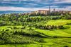 Aerial view of the town of Pienza, Italy seen with rolling hills and tall trees.
