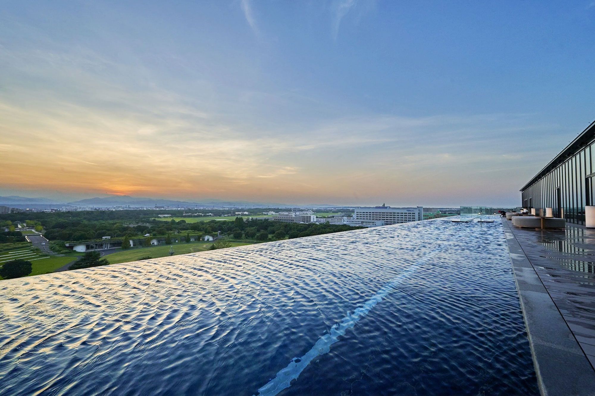 An infinity pool overlooking a green landscape and a mountain and city in the distance.