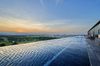 An infinity pool overlooking a green landscape and a mountain and city in the distance.