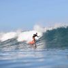 Surfer Chelsea Woody rides a wave on a red surfboard